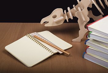 Image showing Model of dinosaur, school board and pile books, notebook