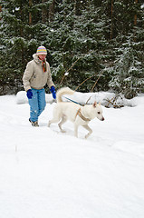 Image showing Woman with a white dog on a walk in the woods during a snowfall