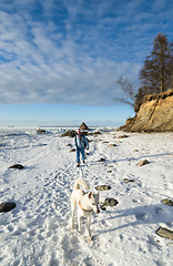 Image showing Woman with a dog walk on a sunny winter day on the coast of the