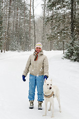 Image showing Woman with a dog on a walk in the woods during a snowfall