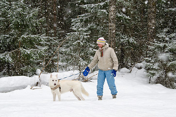 Image showing Woman with a dog on a walk in the woods during a snowfall