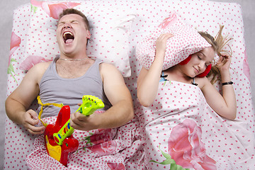 Image showing husband plays guitar, wife covered her pillow