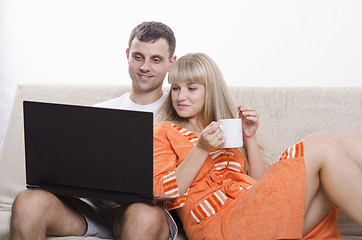 Image showing guy sitting with his laptop on couch, girl Cup of tea