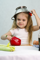 Image showing Girl playing in cook put a colander on his head