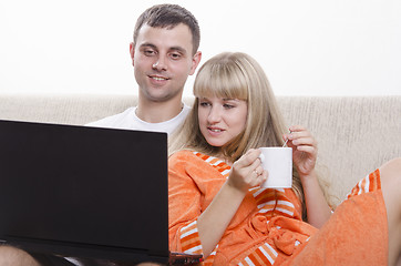 Image showing guy sitting with his laptop on couch, girl Cup of tea