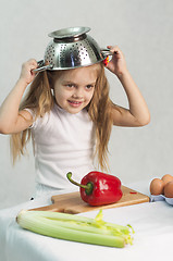 Image showing Girl playing in cook put a colander on his head