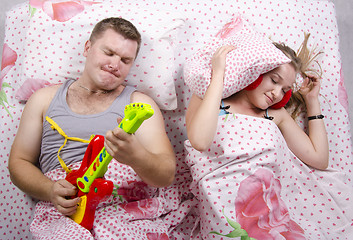 Image showing husband plays guitar, wife covered her pillow