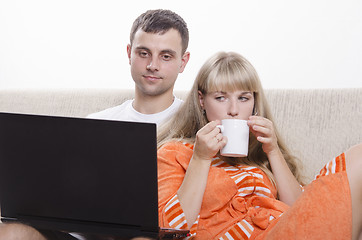 Image showing guy sitting with his laptop on couch, girl Cup of tea