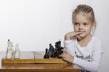 Image showing Four-year-old girl with a sly look, plays chess