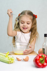 Image showing Girl playing cook churn whisk eggs in a glass bowl