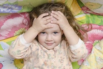Image showing Two-year-old girl lying on bed and head in his hands