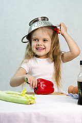 Image showing Girl playing in cook put a colander on his head