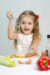 Image showing Girl playing cook churn whisk eggs in a glass bowl