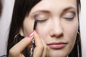 Image showing Makeup artist colors upper eyelids model