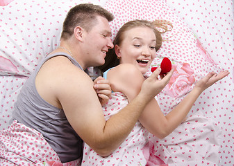 Image showing young man gives a ring girl lying in bed