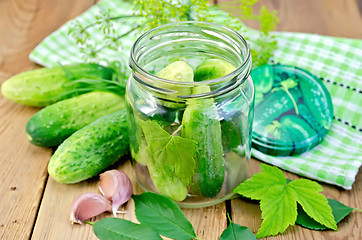 Image showing Cucumbers in jar with leaves and napkin on the board