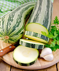 Image showing Zucchini green striped with a knife on board