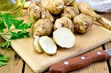 Image showing Jerusalem artichoke is sliced with a knife on board