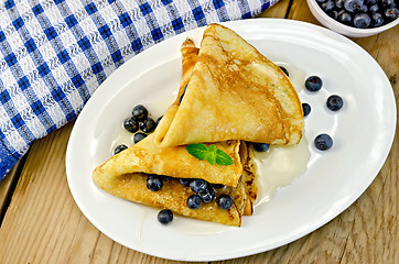 Image showing Pancakes with blueberries and honey on the board