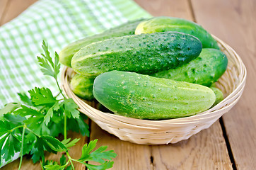 Image showing Cucumbers with parsley in wicker basket on a board