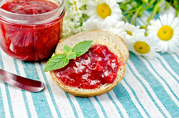 Image showing Bread with strawberry jam and knife on a napkin