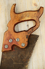 Image showing old rusty saw on wooden background