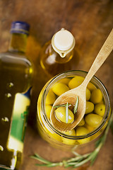 Image showing Close up green olives in bank,  bottle of olive oil, rosemary