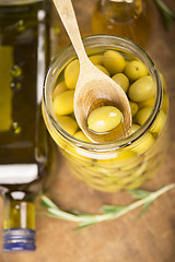 Image showing Close up green olives in bank,  bottle of olive oil, rosemary