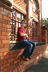 Image showing Child sitting on brick wall