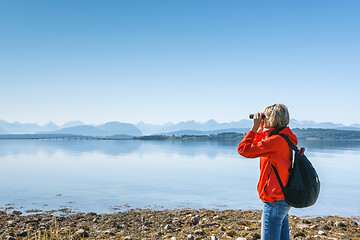 Image showing Woman tourist looking through binoculars at distant Atlantic Road, Norway