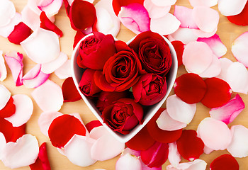 Image showing Red rose inside the heart shape bowl with petal beside