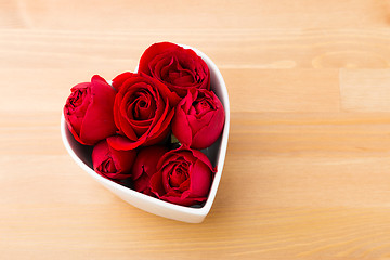 Image showing Red rose inside the heart shape bowl on wooden background