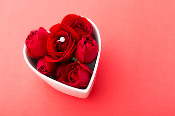 Image showing Red rose and diamond ring inside heart shape bowl over the red b