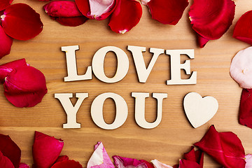 Image showing Wooden letters forming phrase Love You with rose petal besides