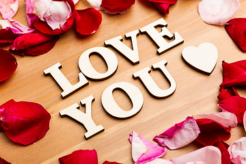 Image showing Love You wooden letters with rose petal besides
