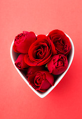 Image showing Red rose inside the heart shape bowl with red background