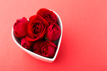 Image showing Rose inside the heart shape bowl over the red background