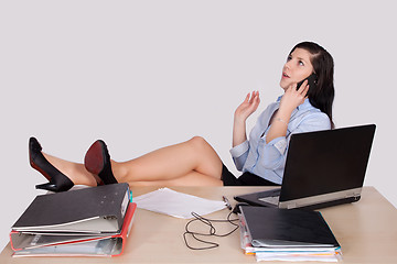 Image showing Young female office worker with feet on desk