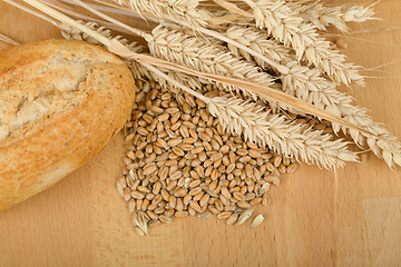 Image showing roll on wooden table with ears of wheat grain