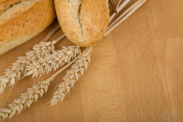 Image showing roll on wooden table with ears of wheat grain