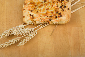 Image showing Freshly bread with cheese and onion on wooden table with ears