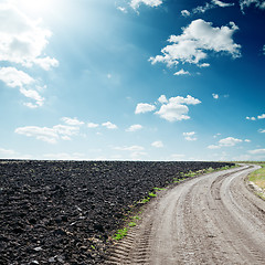 Image showing sun in dramatic sky over road near black field