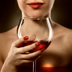 Image showing woman in red holding wine glass and smiles