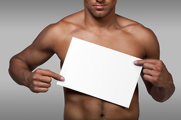 Image showing Muscular naked man holding white empty paper