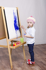 Image showing Girl artist paints on canvas