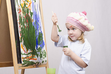 Image showing Girl artist paints on canvas