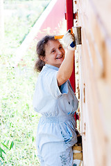 Image showing Pretty woman painting her house