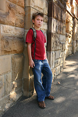 Image showing Youth leaning against sandstone wall