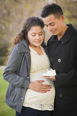 Image showing Hispanic Pregnant Couple Holding Baby Shoes Outside