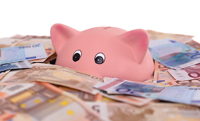 Image showing Unique pink ceramic piggy bank drowning in money